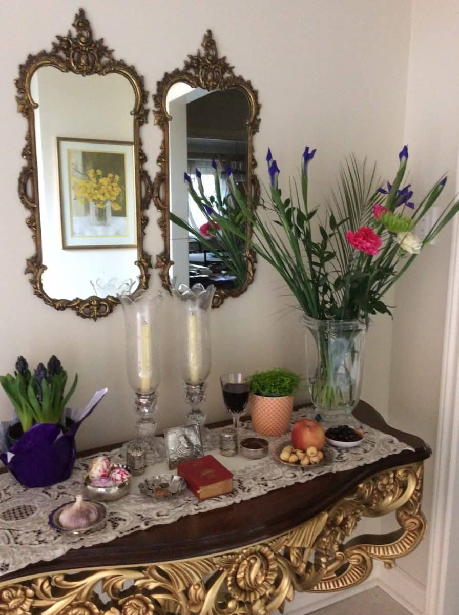 Ornate wall mirrors next to a vase of colorful flowers on a decorated table.