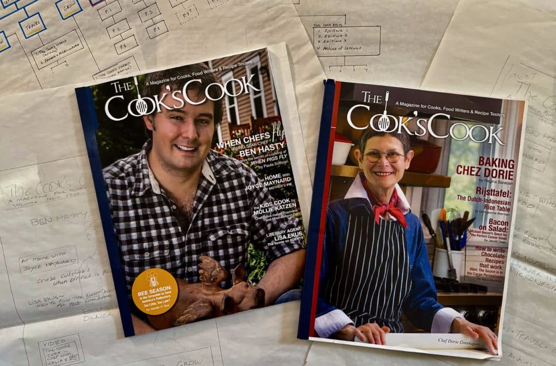 The first two issues of The Cook's Cook magazine, on a background of papers.