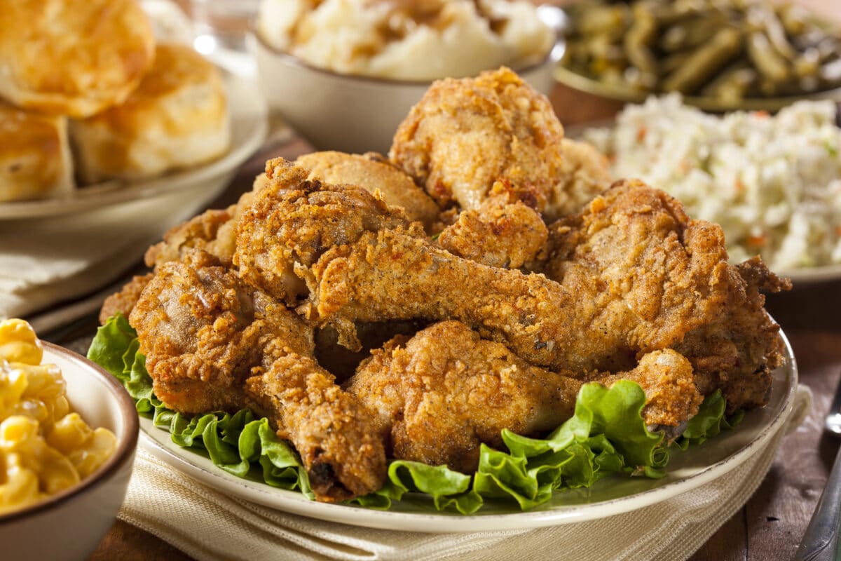 Fried chicken in a china bowl with biscuits and mashed potatoes.