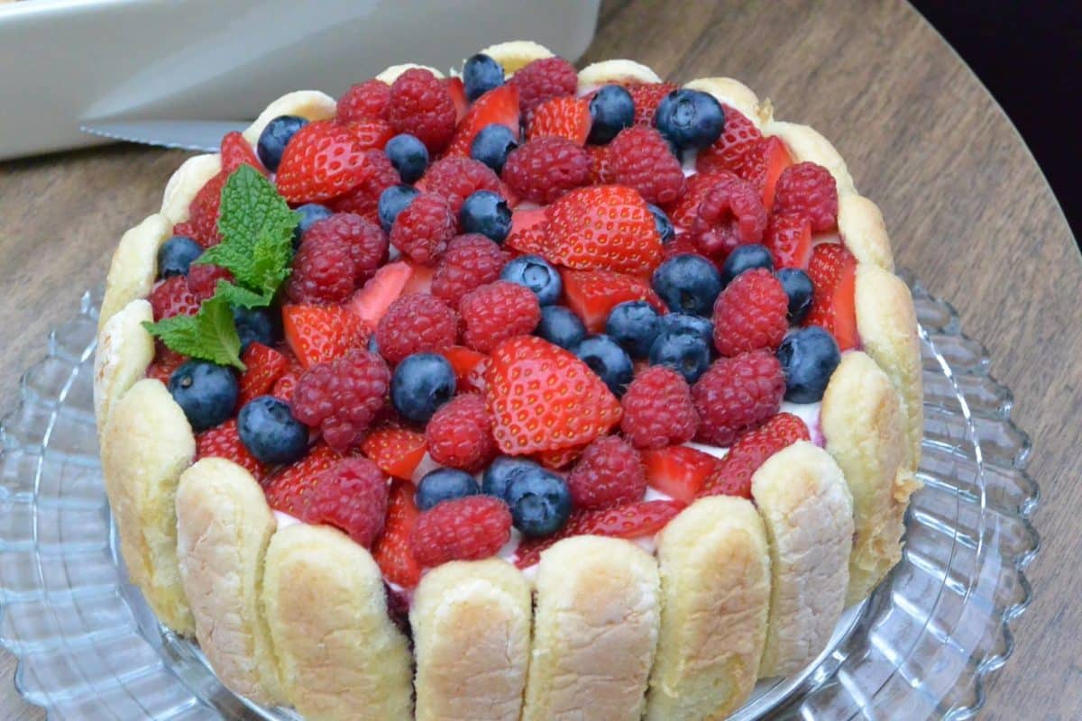 A luscious berry cake garnished with strawberries, raspberries, and blueberries.