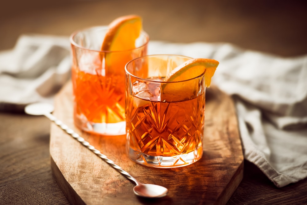 Close-up of two cocktail glasses filled with a vibrant orange cocktail and adorned with an orange slice.