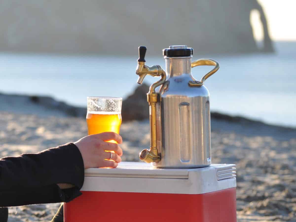 Hand pouring beer from a stainless steel uKeg Growler