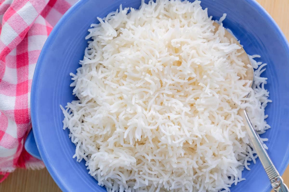 Fluffy cooked basmati rice served in a vibrant blue bowl.