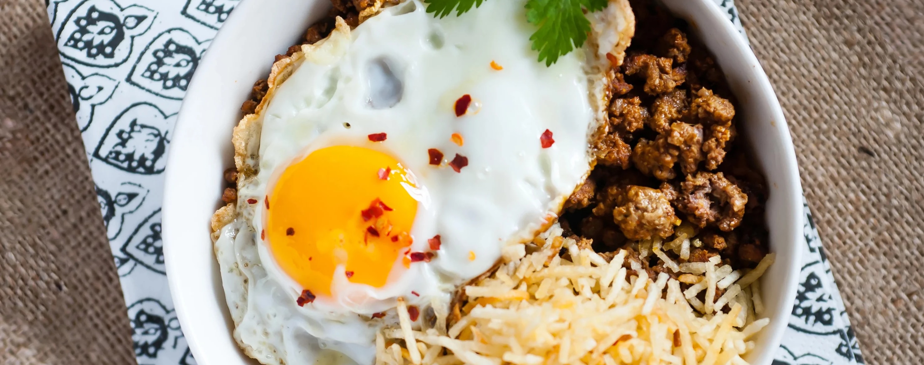Kheemo, sali  nay eedu. Ground meat topped with potato straws and a fried egg.