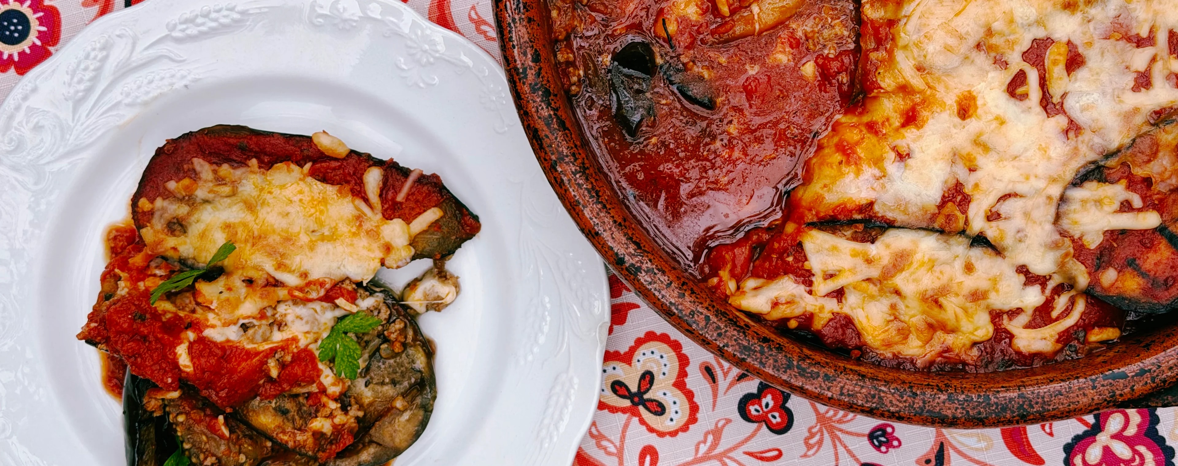 Charcoal-grilled eggplant parmigiana layered with seasoned ground veal, homemade tomato sauce, Parmesan, and golden melted mozzarella in a rustic baking dish.