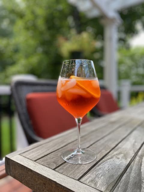 A close-up of an Aperol Spritz drink with an orange slice garnish