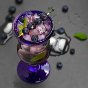 Close-up of a blueberry mocktail with fresh blueberries and mint leaves.