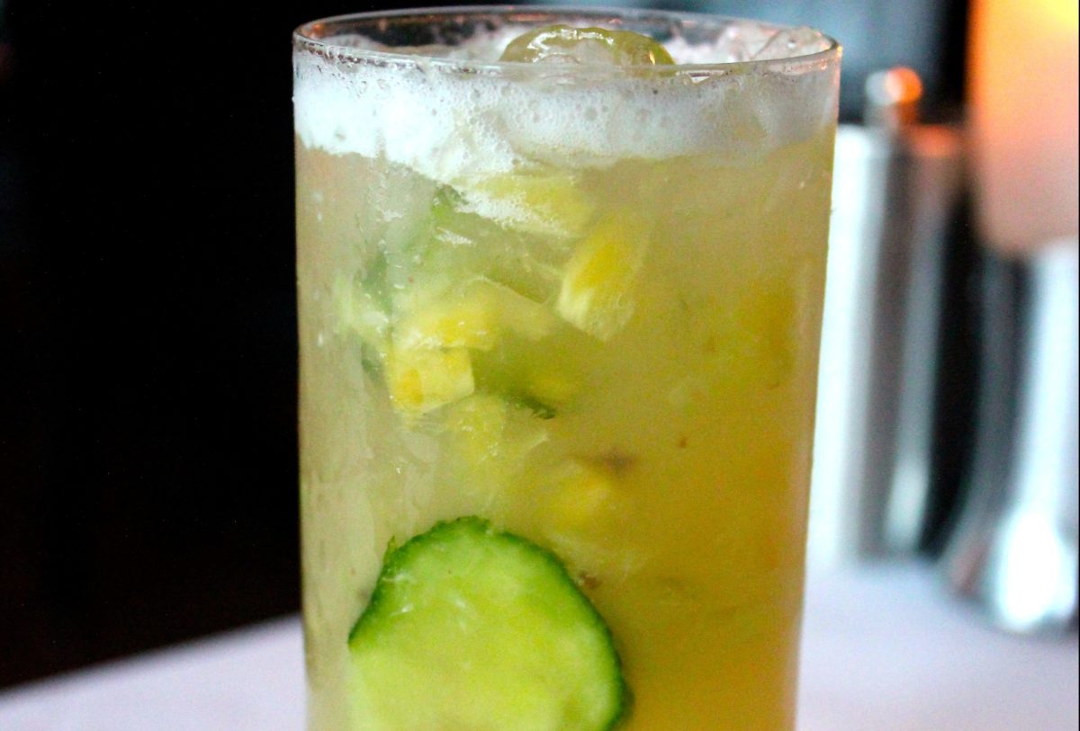 A refreshing cocktail with cucumber slices and crushed ice.