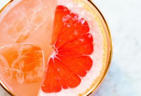 Top view of a cocktail with half a grapefruit slice and rimmed with salt.