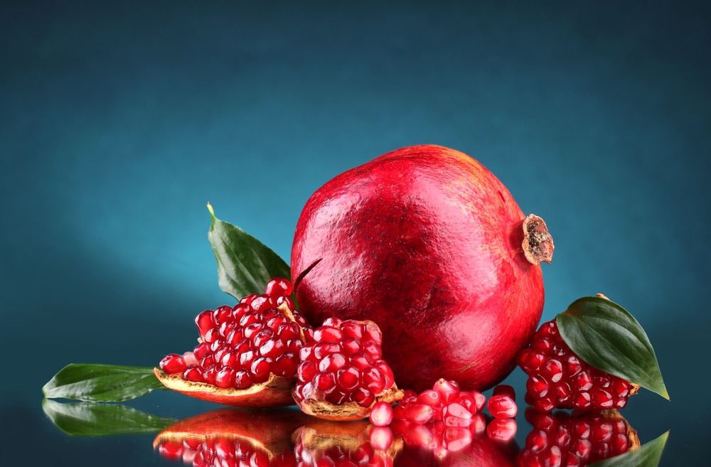 Cocktail with pomegranate seeds and green leaves