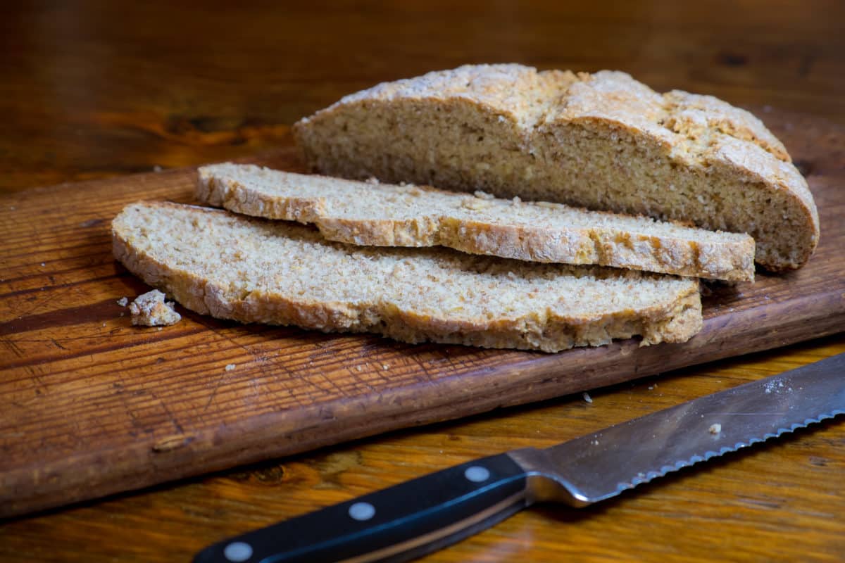 Freshly sliced Irish Wheaten Bread on a wooden cutting board next to a knife.