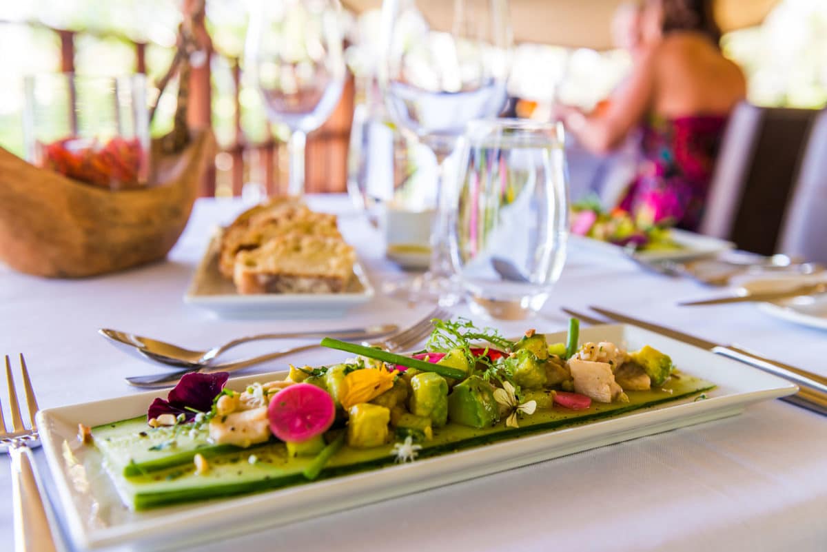 A vibrant plate of tilapia ceviche with ingredients like lime, cucumber, avocado, and pickled radish.